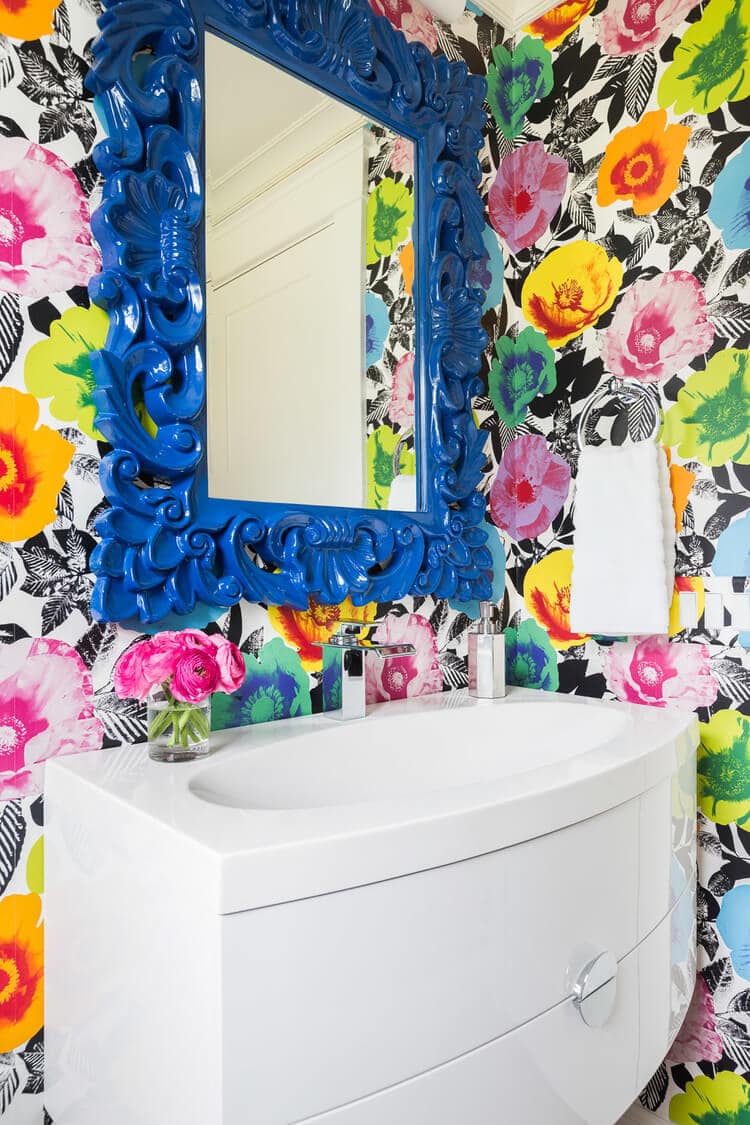 powder room with colorful bright floral wallpaper and blue painted mirror